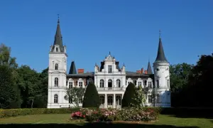Imponujący pałac w Posadowie z wieżami i ozdobnym ogrodem.