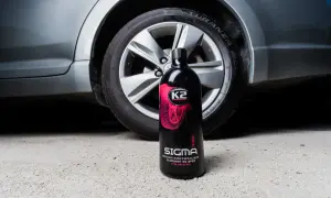 Butelka preparatu K2 Sigma Pro do pielęgnacji opon, stojąca obok koła samochodu. Płyn pomoże Ci zadbać o to, jak przechowywać opony, by służyły dłużej.