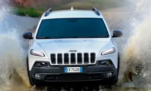 Biały Jeep Cherokee Trailhawk z impetem wjeżdża w wodę, tworząc efektowne rozbryzgi.