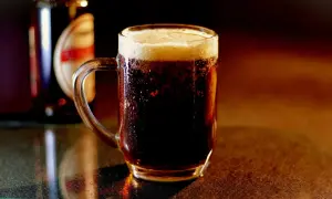 Chłodny, ciemny lager z gęstą pianką w szklanym kuflu, obok butelki.
