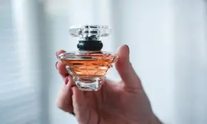 Dłoń trzyma flakonik perfum o bursztynowym kolorze. Wygląda jak dzieło sztuki, może to baccarat kurkdjian?