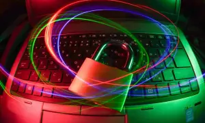 Kłódka na klawiaturze laptopa, otoczona kolorowymi światłami, symbolizuje bezpieczeństwo i ochronę, jak dobry antywirus na Linuxa.