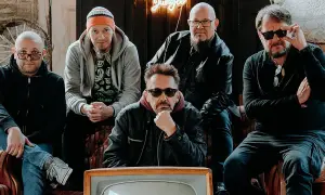 Pięciu mężczyzn, zespół Sztywny Pal Azji, siedzi na kanapie. W tle neonowy napis "Jungle".