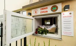 Okno życia z koszykiem, białym kocykiem i czerwonymi różami. To miejsce nadziei dla noworodków.