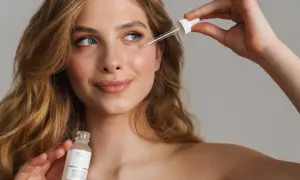 Młoda kobieta aplikuje serum z pipetką na twarz. Czy to peptydy?