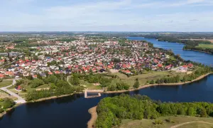 Widok z lotu ptaka na miasteczko nad jeziorem, z dachami domów i zielenią. To największy rynek w Polsce, tętniący życiem.