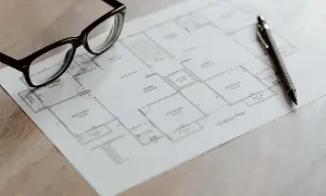 Occhiali e penna su una planimetria, pronti per analizzare il cambio categoria catastale di un immobile.