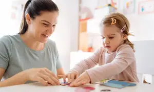 Bambina e maestra giocano con i puzzle in un asilo nido.