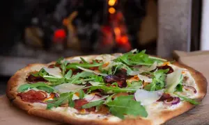 Pizza bianco med salami, ruccola och parmesan. En läcker pizza som precis kommit ut ur ugnen.