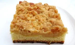 Ein Stück saftiger Streuselkuchen vom Blech mit goldbraunen, knusprigen Streuseln auf hellem Teig.