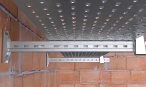 Soportes metálicos fijados a pared de ladrillo con anclajes químicos, sosteniendo una bandeja perforada.