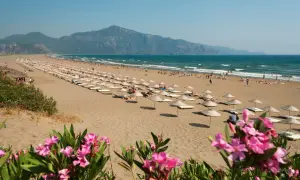 Piękna plaża w Turcji, gdzie turcja w marcu pogoda sprzyja relaksowi pod parasolami. W tle góry i turkusowe morze.