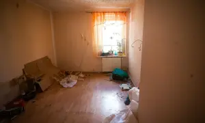 Zalane mieszkanie, stosy kartonów, klatka dla ptaków i worki. Spółdzielnia ponosi odpowiedzialność za zalanie mieszkania, co widać po zniszczeniach.