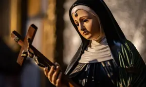 Figurka zakonnicy z krzyżem, symbol nadziei i anioł od spraw beznadziejnych, w świetle świec.