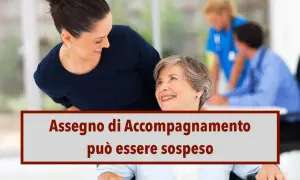 Giovane donna sorride a un'anziana in carrozzina. Testo: "Assegno di accompagnamento può essere sospeso".