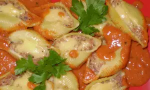 Nadziewane muszle makaronowe mięsem mielonym, zapieczone z serem i polane sosem pomidorowym.