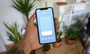 Main tenant contrôle la température de sa maison avec une application tado homekit sur son smartphone.