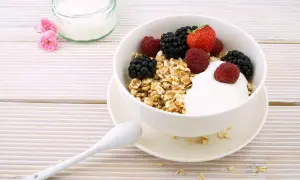 Un delizioso yogurt a colazione con muesli e frutti di bosco freschi, pronto per iniziare la giornata con energia e gusto.