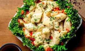 Pyszne pierogi ze szpinakiem, posypane koperkiem i papryką, otoczone sałatą. Idealne na obiad!