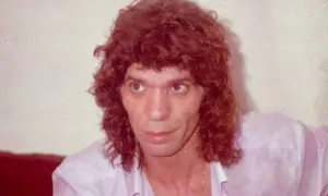 Primer plano de un hombre con cabello rizado y camisa rosa. Se especula a qué edad murió Camarón.