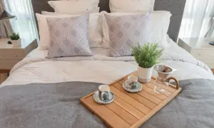 Eleganckie ścielenie łóżka z dwoma ozdobnymi poduszkami i tacą z kawą.