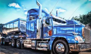 Un camion us bleu étincelant, prêt pour la route. Le chrome brille sous le ciel bleu.