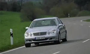 Srebrny Mercedes W211 z 2004 roku jedzie po krętej drodze wśród zielonych wzgórz.