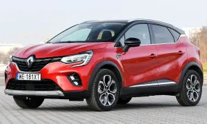 Czerwony Renault Captur 2025 z czarnym dachem, zaparkowany na kostce brukowej. Stylowy SUV gotowy na miejskie przygody.
