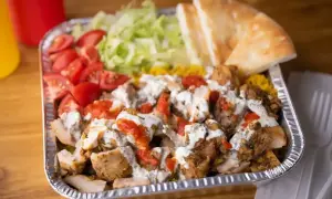 Pyszna shoarma z kurczaka z ryżem, pomidorami, sałatą i chlebkiem pita, polana sosem.