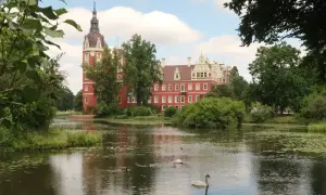 Zamek w Mużakowie zachwyca czerwienią i wieżą. Wokół jezioro z łabędziami, idealne miejsce na zwiedzanie.