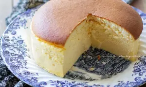 Una soffice torta giapponese, con una fetta mancante, servita su un piatto decorato con un motivo blu e bianco.