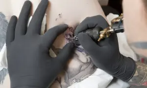Artysta tworzy tatuaże oldschool wzory, tatuując kota na skórze.