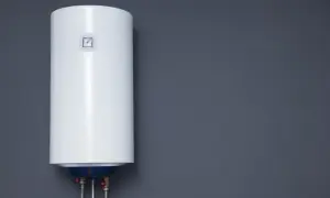 Biały bojler elektryczny wiszący na szarej ścianie.