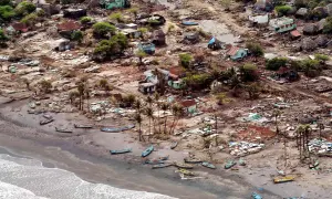 En by ödelagd av tsunamin 2004. Hus är raserade, båtar ligger utspridda på stranden. Bilden ger en känsla av förödelsen och väcker frågan: hur många dog i tsunamin 2004?