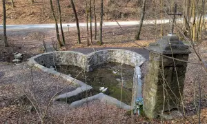 Kamienny, sercowaty basen z wodą i krzyżem obok, przypominający diabelski most w Czarnej.