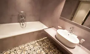 Baño moderno con microcemento en paredes y suelo de baldosas hidráulicas. Bañera y lavabo de diseño.