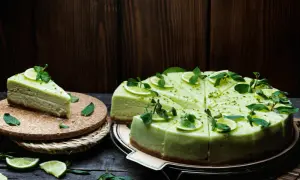 Zielony, orzeźwiający sernik pistacjowy, udekorowany plasterkami limonki i listkami mięty, kusi swoim wyglądem.