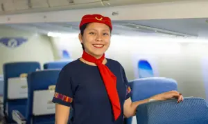 Uśmiechnięta stewardessa w granatowym mundurku i czerwonym beretku, gotowa do lotu. Marzysz, jak zostać stewardessą?