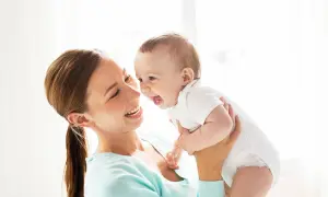 Szczęśliwa mama trzyma roześmiane dziecko. Zastanawiasz się, ile pieluch dziennie dla noworodka?