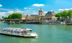 Bateau touristique sur la Seine, avec l'Institut de France et un pont en arrière-plan. Une belle journée pour une visite Paris Seine.