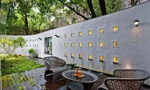 Elegante decoracion patio exterior con muebles de mimbre, cascadas y luces cálidas en la pared.