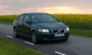 Ciemnozielone Volvo S40 2.0 diesel jedzie wiejską drogą pośród kwitnącego rzepaku.