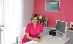 Lekarka w gabinecie dermatologii estetycznej, siedzi przy biurku.
