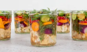 Sechs Gläser mit bunten Gemüsesorten wie Blumenkohl, Karotten, Gurken und Zwiebeln, bereit für mixed pickles selber machen.