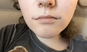 Dwa kolczyki dahlia piercing zdobią usta, dodając odważnego charakteru.