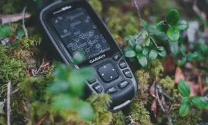Garmin inReach, jako akcesoria do komunikacji satelitarnej, leży na mchu w lesie.