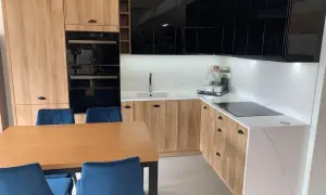 Nowoczesna kuchnia z drewnianymi frontami i białym blatem kamiennym. Zastanawiasz się, ile kosztuje metr blatu kamiennego?
