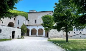 Cortile di un antico complesso monastico in pietra, con un portico ad archi. Ideale per chi cerca la fonte avellana come arrivare.