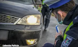 Policjant sprawdza, czy ledy pod autem są legalne. Mundurowy z Lubuskiej Policji bada oświetlenie pojazdu.