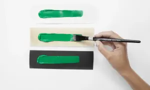 Pennello stende vernice acrilica su carta bianca, legno e nera. La vernice acrilica a cosa serve? A creare effetti vibranti su diverse superfici.